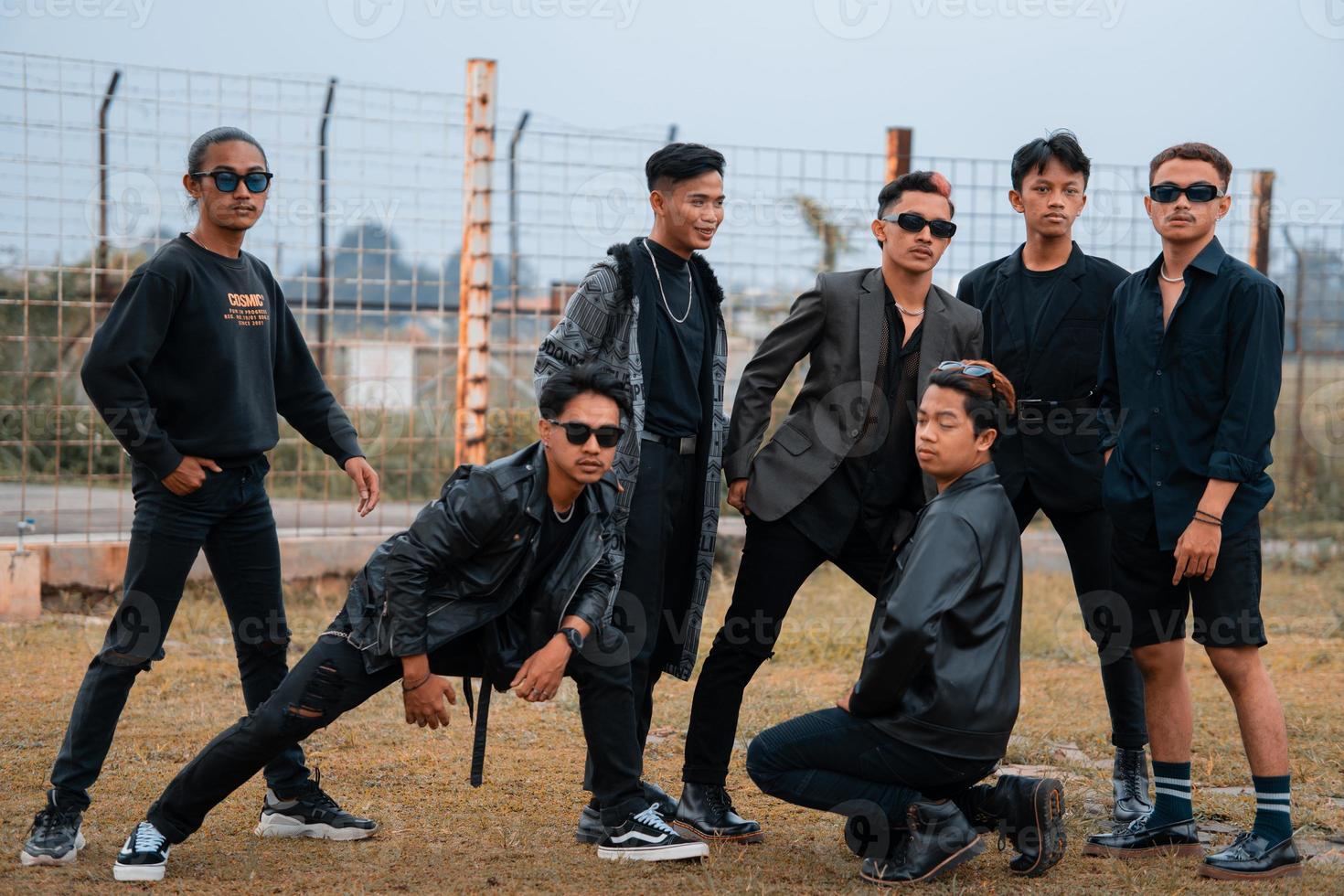 a group of teenage boys in black clothes posing very gallantly with their friends in a field photo