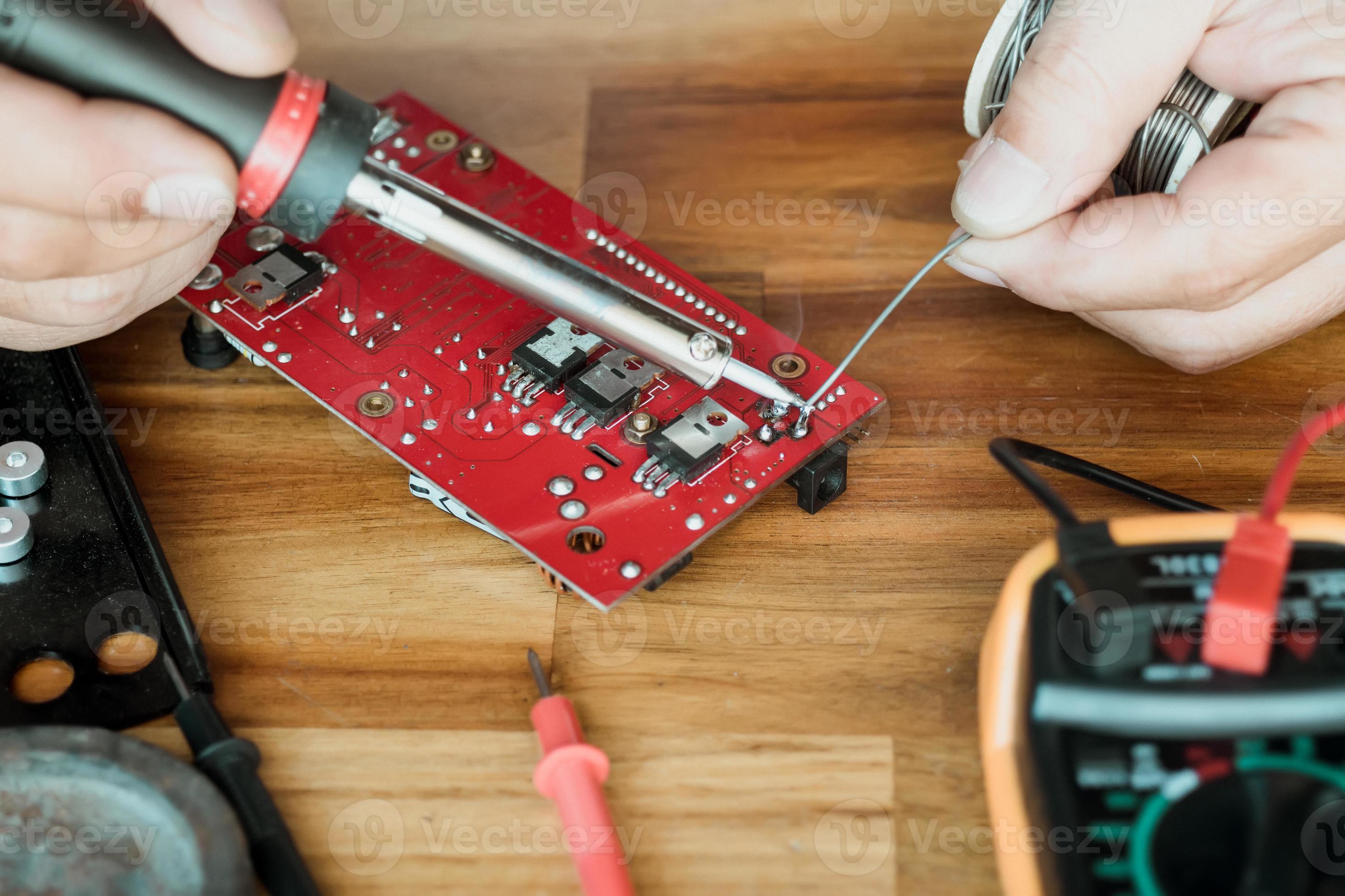 technician man holding iron solder and repairing the circuit board by