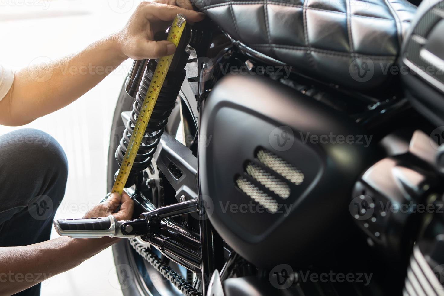 mechanic using tape measure set up suspension sag Compression and Rebound on motorcycle at garage,  repair and maintenance motorcycle concept .selective focus photo