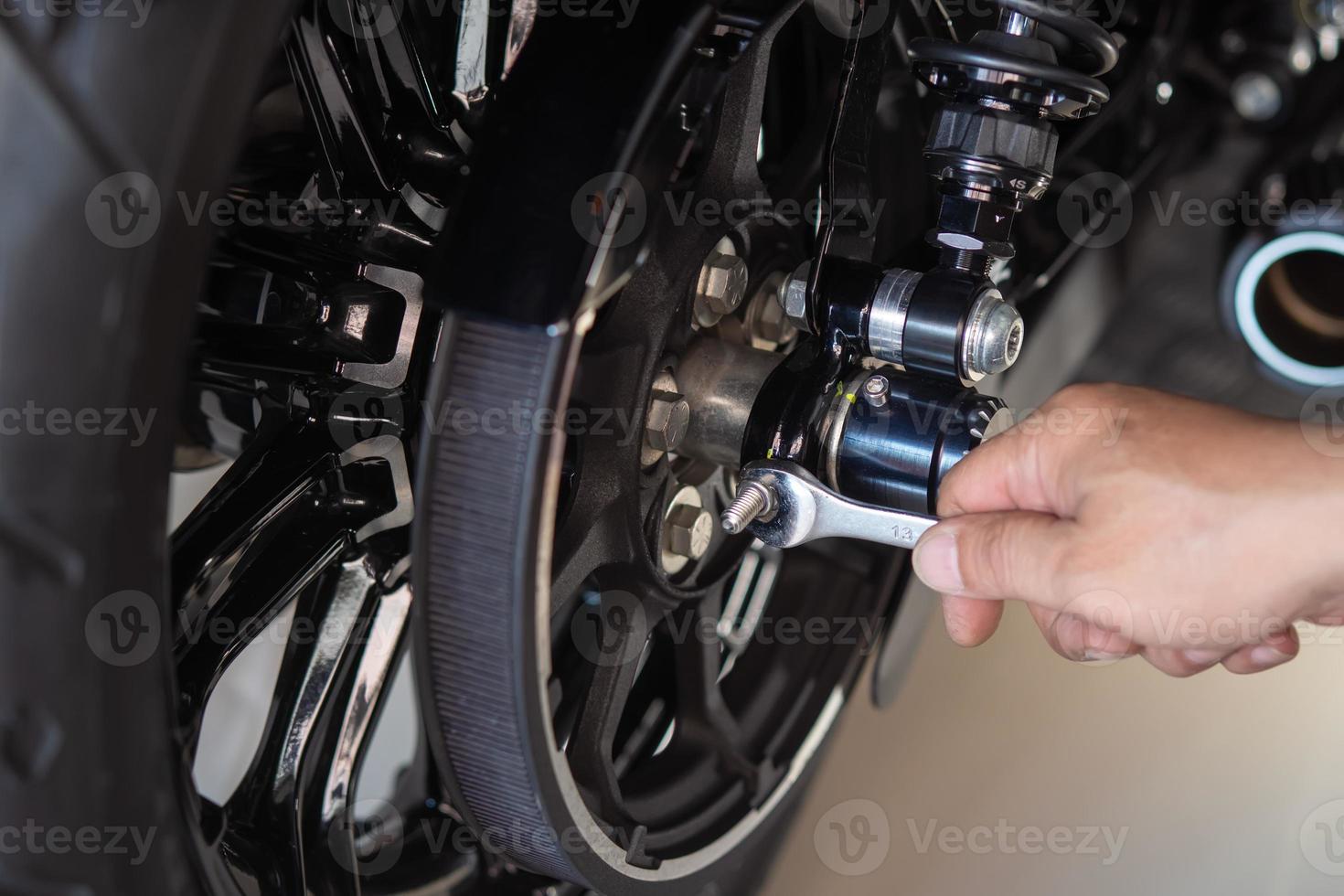 motorcycle mechanic use a wrench Adjust the belt pulley tension and drive belt on motorcycle working in garage .maintenance and repair motorcycle concept .selective focus photo