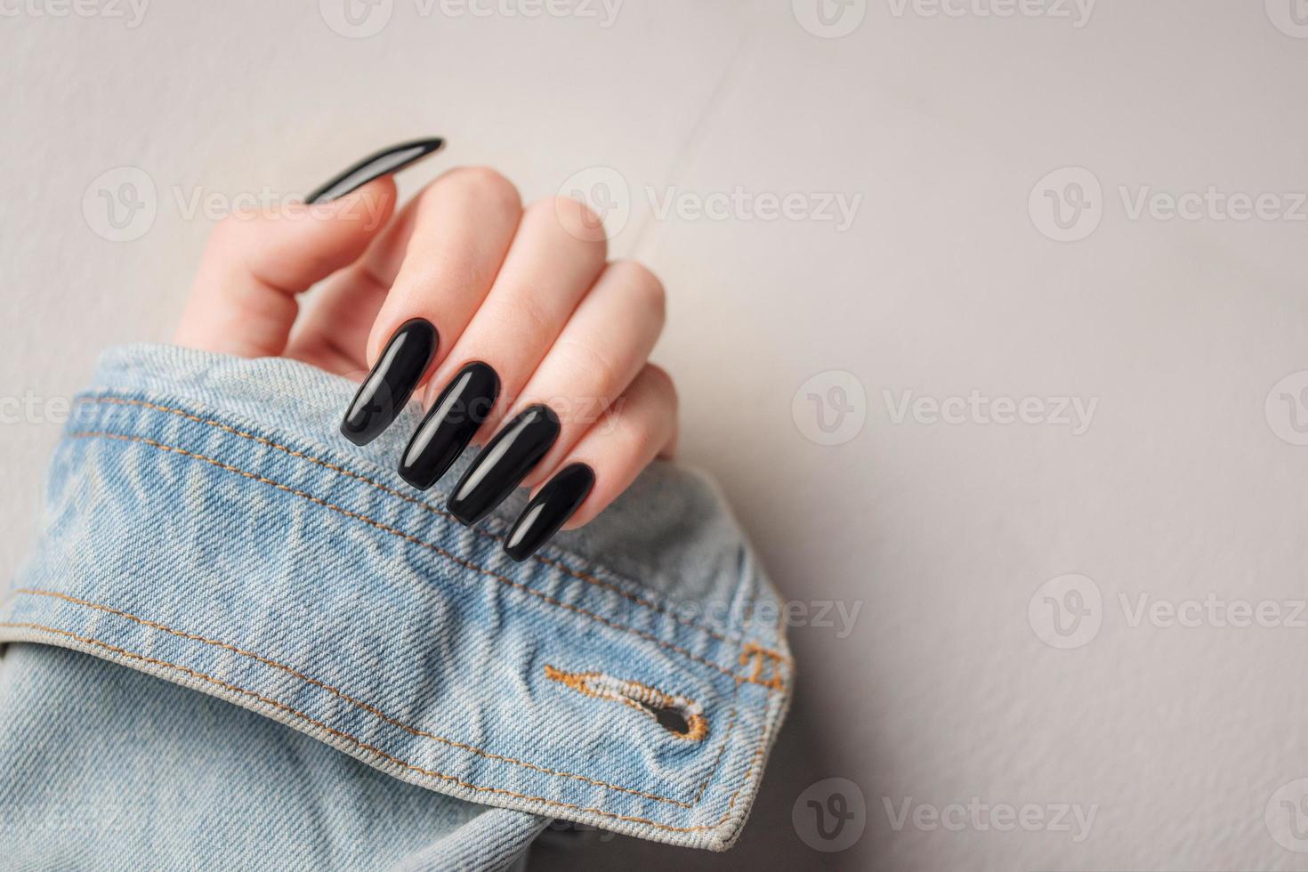 mano de una joven con manicura negra en las uñas foto