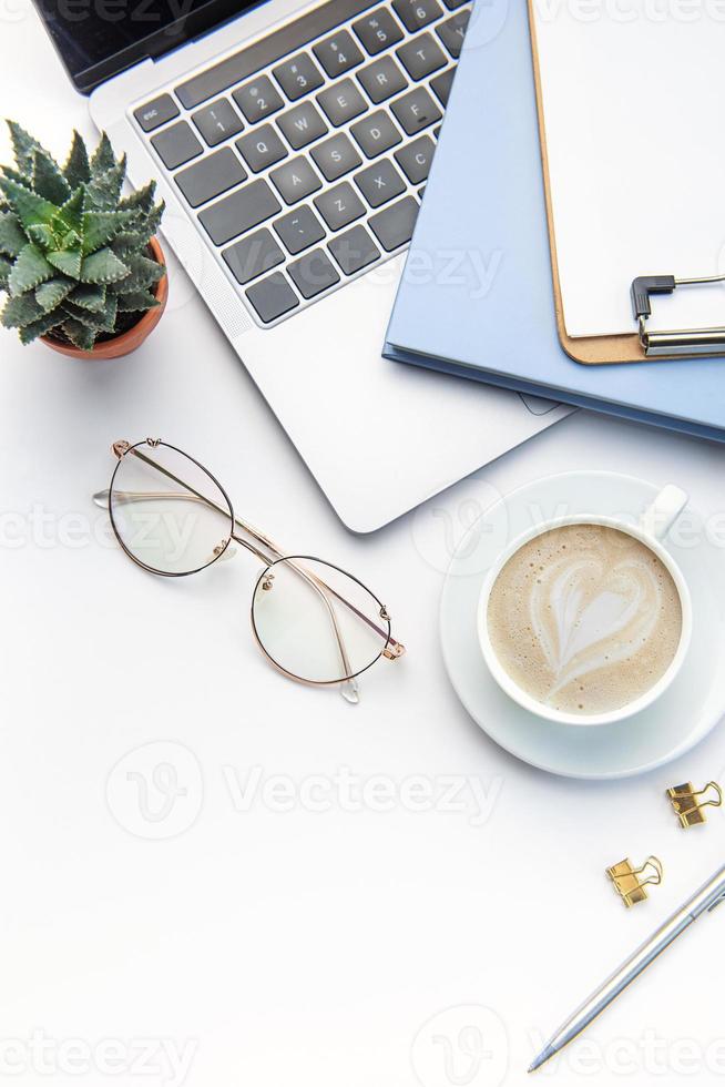 Modern white office desk table with laptop, notebook and other supplies. photo