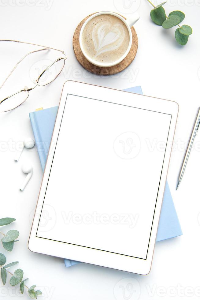 Modern white office desk table with tablet, notebook and other supplies. photo