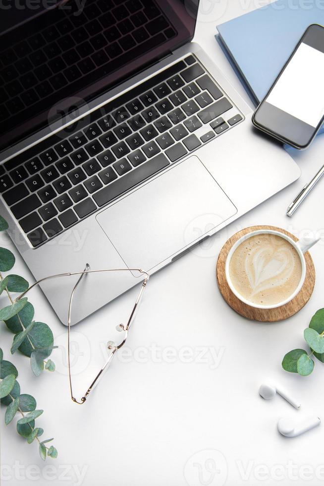 Office desk table with laptop, supplies and coffee cup photo