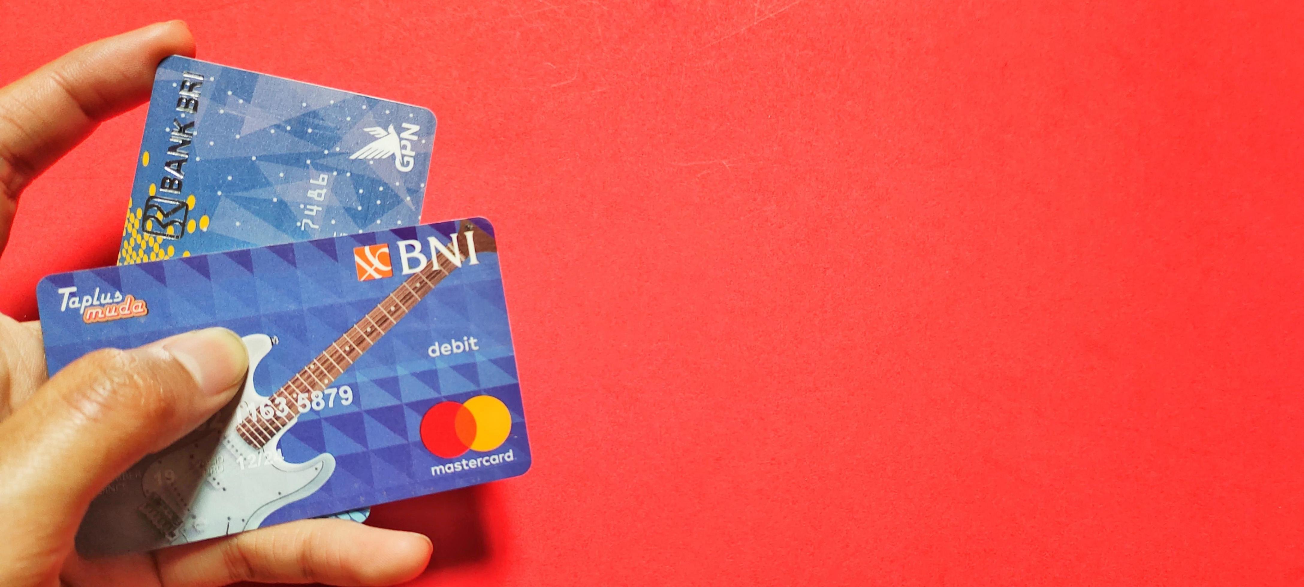Man holding a bank savings card in Indonesia, isolated on a red