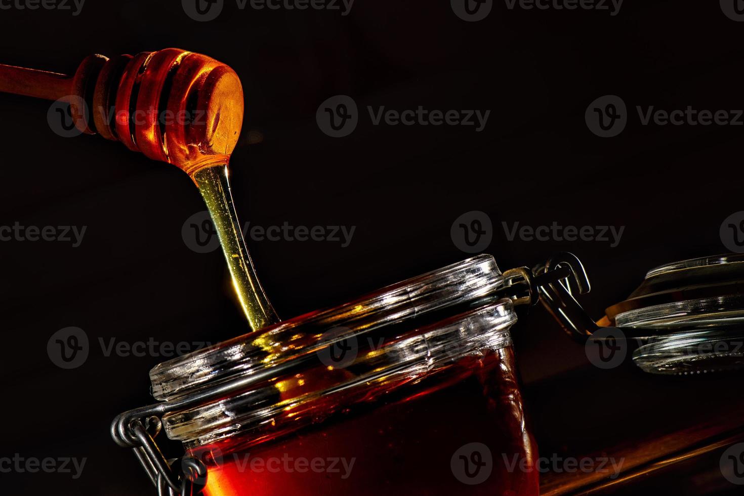 Glass jar with honey and the natural wooden stick photo