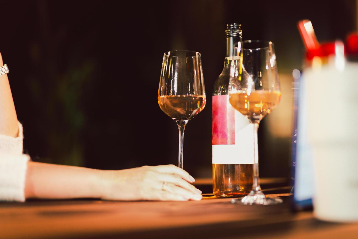 mujer mano participación vino vaso en cena mesa en el restaurante. foto