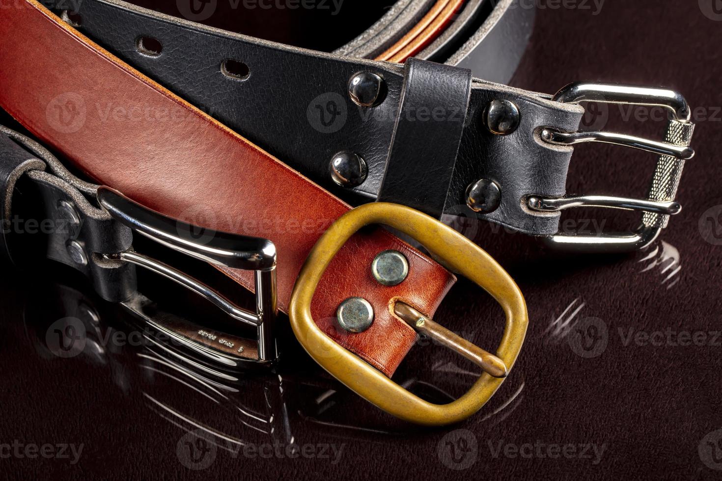varios cuero cinturones con un metal hebilla en un oscuro antecedentes. foto