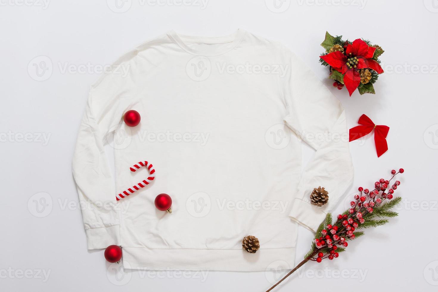 Close up white blank template sweatshirt copy space. Christmas Holiday concept. Top view mockup sweatshirt. Red holidays decorations on white background. Happy New Year accessories. Xmas outfit photo