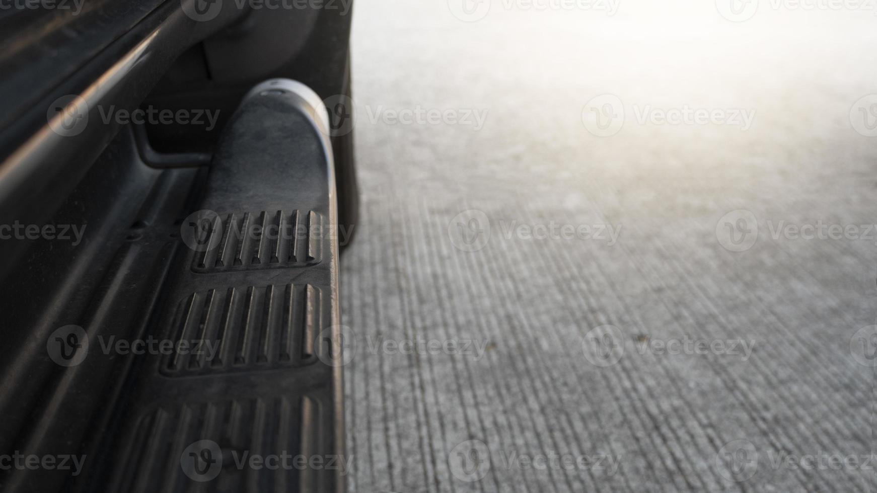 Car side oriented steel railing for stepping up trucks. Blurred background of cement floor. photo