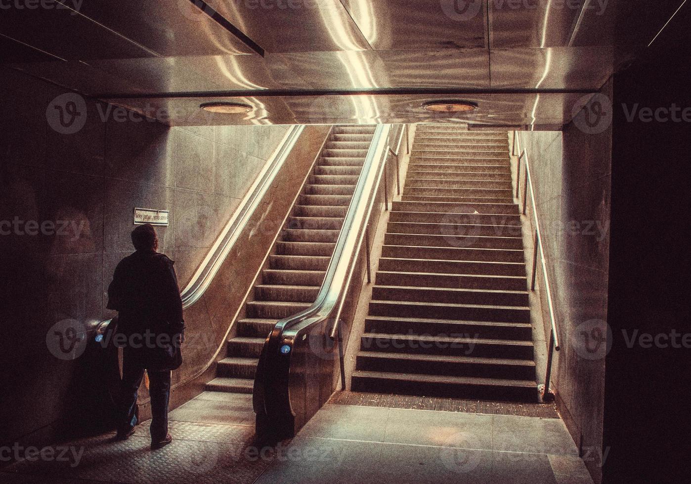 hombre en tren estación escalera mecánica foto