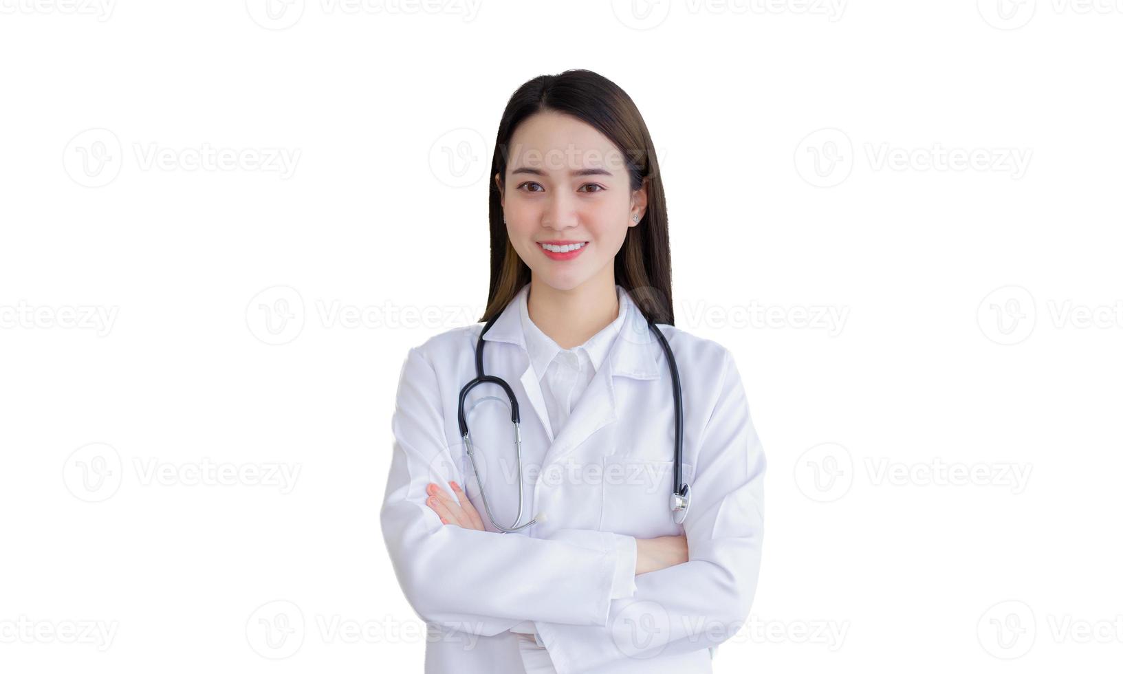 Una doctora profesional asiática con una túnica blanca y un estetoscopio de pie con los brazos cruzados feliz y sonriendo en la sala de examen del hospital. foto