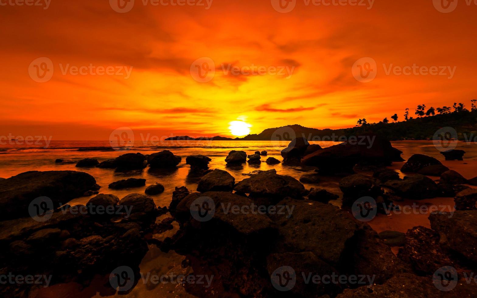 Golden hour sunset. Orange sunset at seaside with rocks photo