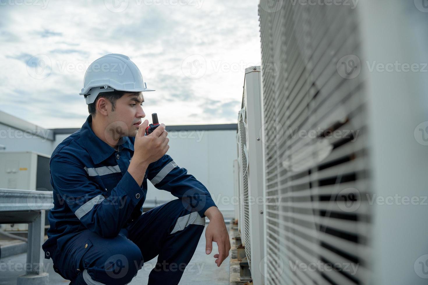 Asian maintenance engineer work on the roof of factory. contractor inspect compressor system and plans installation of air condition systems in construction. technology, walky talky, maintenance photo