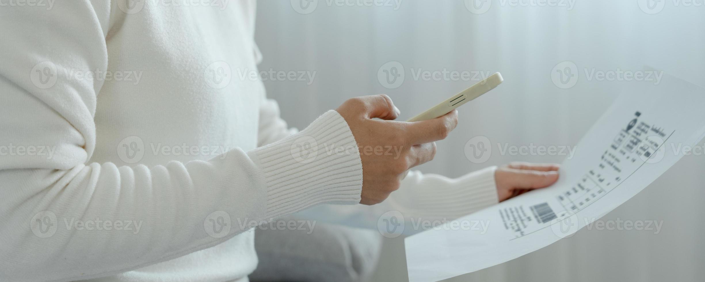 woman use phone scan barcode or QR codes to pay credit card bill after receiving document invoice. payment, receive, paying electricity, digital payments, technology, scanning, financial transactions photo