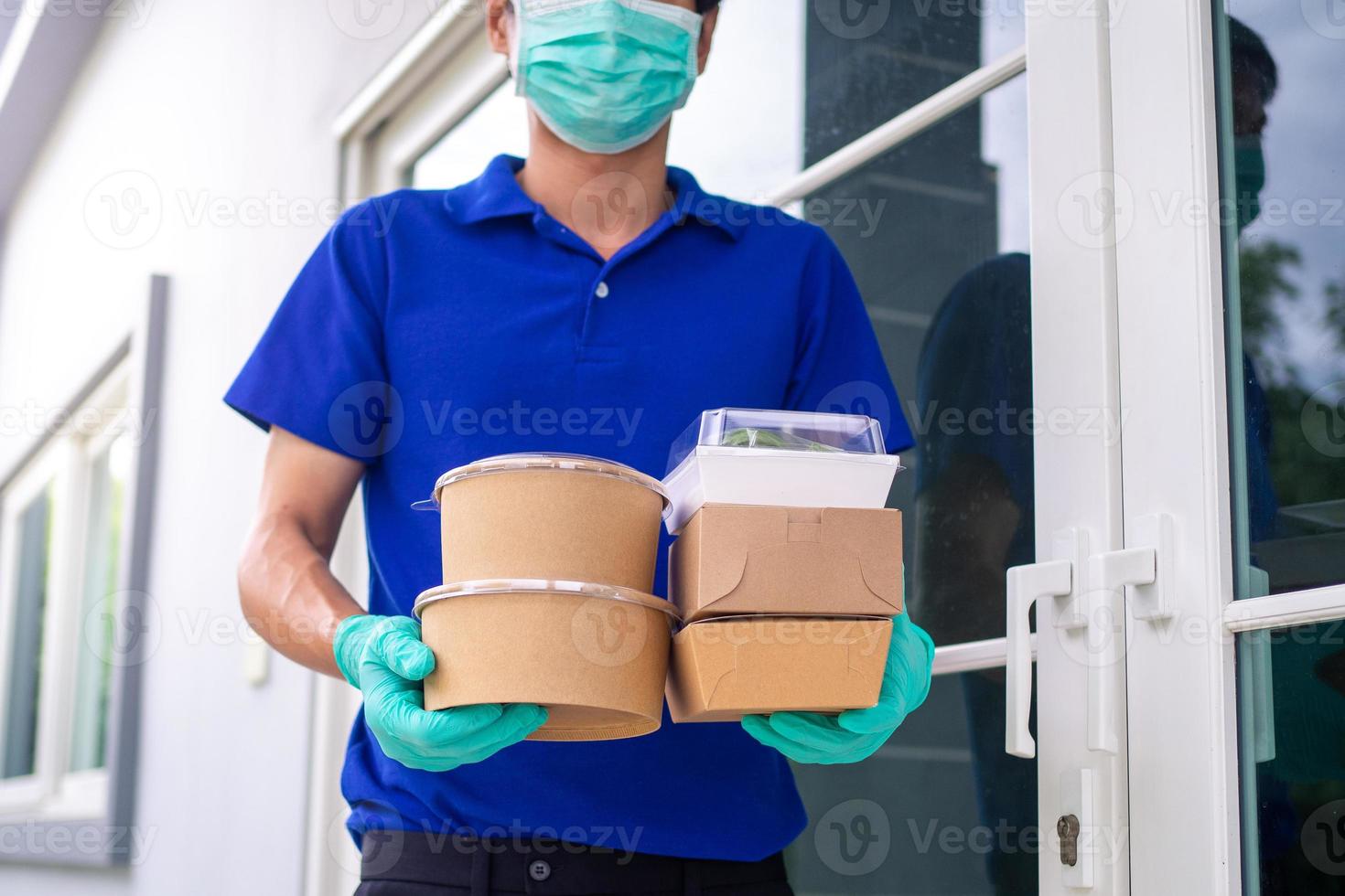 Deliveryman wears a mask and gloves, delivery food to the home of the online buyer. stay at home reduce the spread of the covid-19 virus. The sender has a service to deliver products or food quickly photo