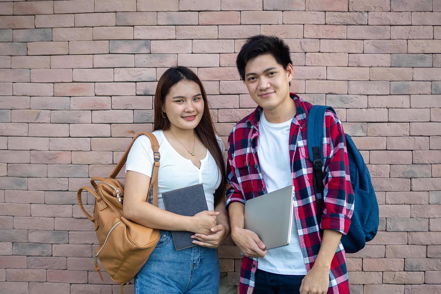 asiático masculino y hembra estudiantes son Listo a Vamos a colegio felizmente, que lleva cuadernos y tabletas y educativo equipo. foto