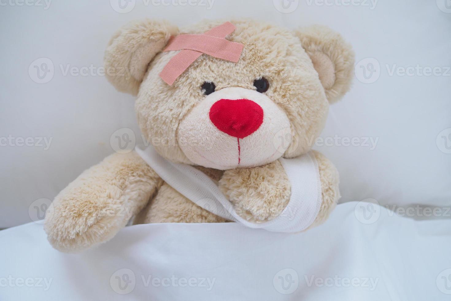 Teddy bear with a wound dress, wound and broken hands. Sleeping in bed. Sickness of children photo