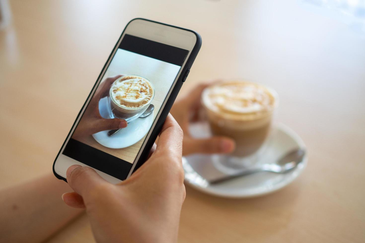 mano participación móvil teléfono o célula teléfono digital cámara tomando foto a taza de caliente café. a actualizar a social