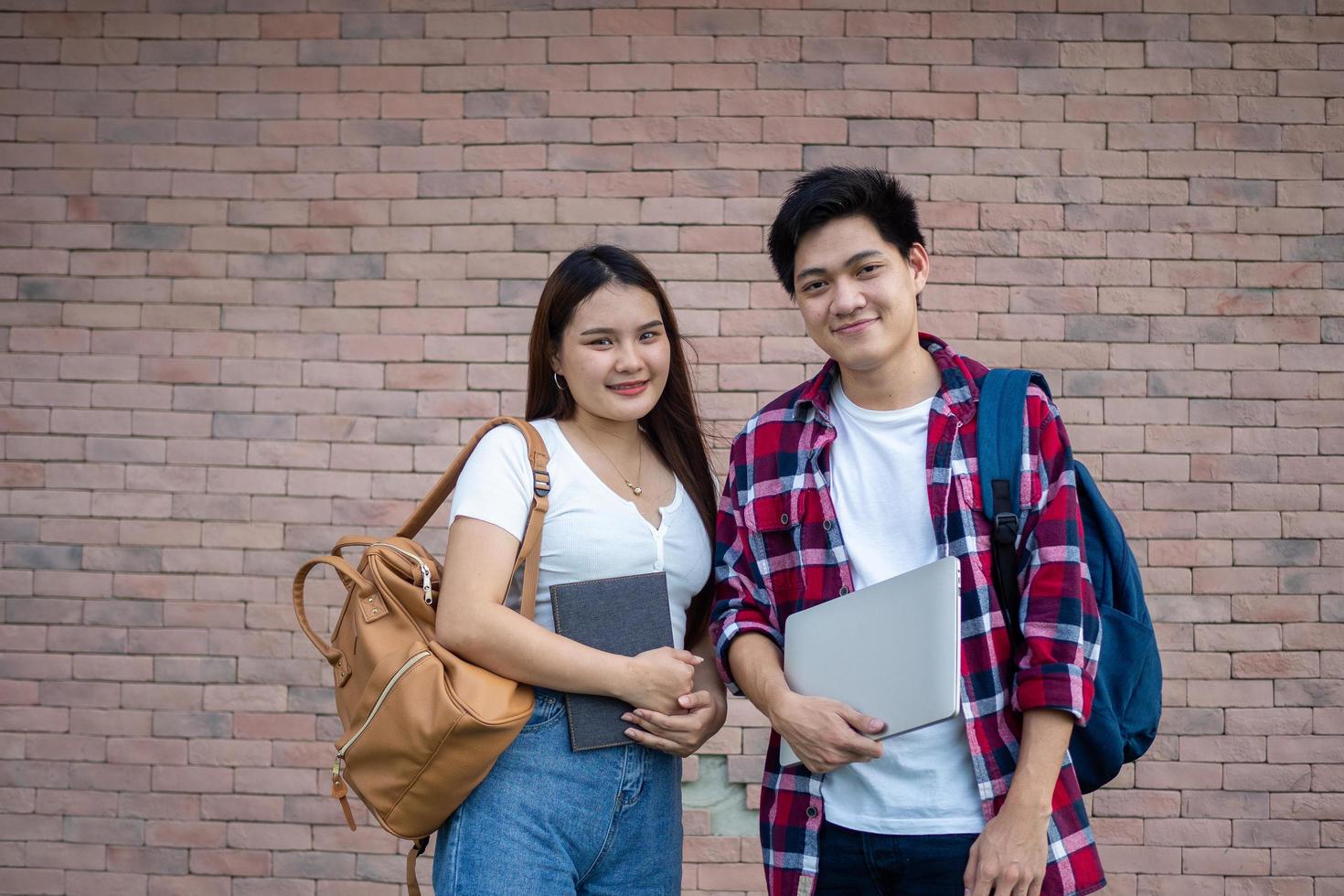 Asian male and female students are ready to go to school happily, carrying notebooks and tablets and educational equipment. photo