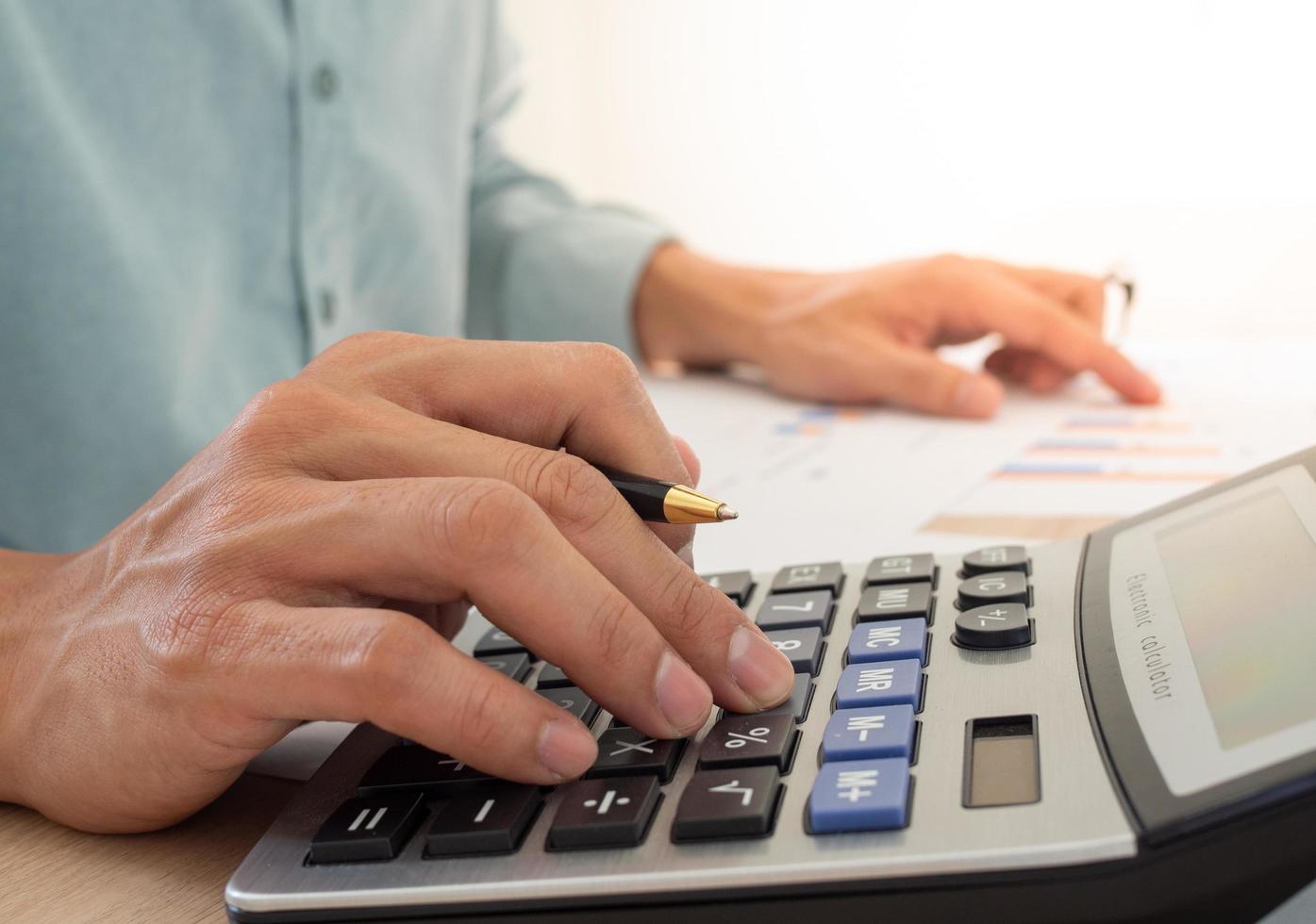 A business man using a calculator to calculate expenses from receipts placed on the table. debt concept photo
