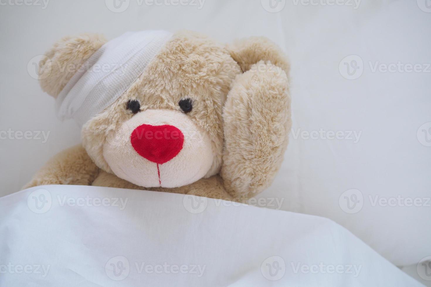 Teddy bear with a wound dress, wound and broken hands. Sleeping in bed. Sickness of children photo