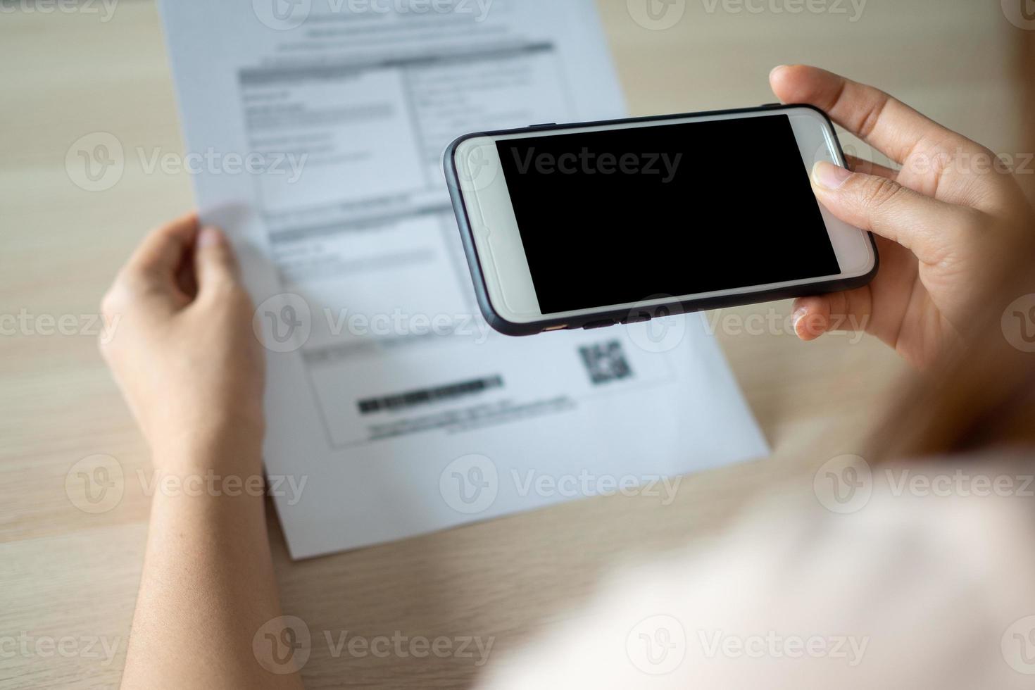The hand uses the phone to scan the QR code to receive a discount from paying electricity bills at the office photo