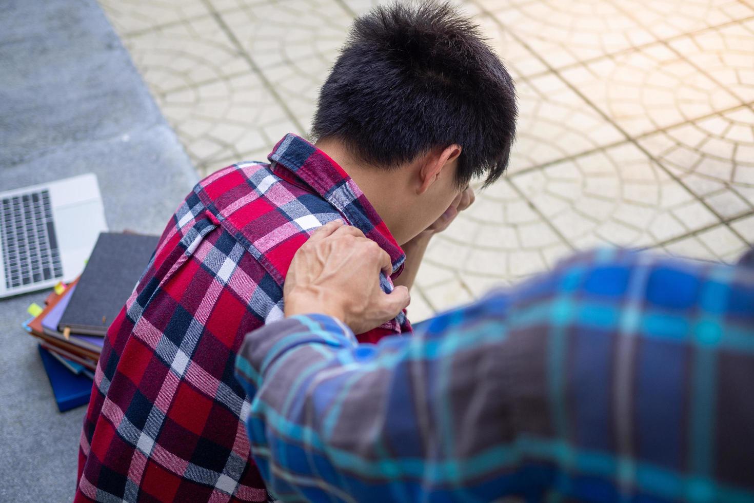 el mano conmovedor el hombro presentado ánimo después el masculino estudiantes fueron decepcionado con el problemas de el prueba resultados o desconsolado con su novia. amistad y cuidando conceptos foto