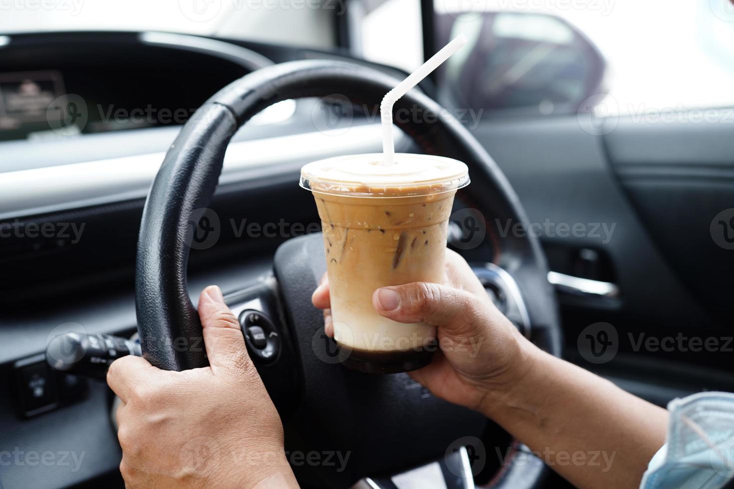 Asian woman driver hold ice coffee cup for drink in car, dangerous and risk an accident. photo