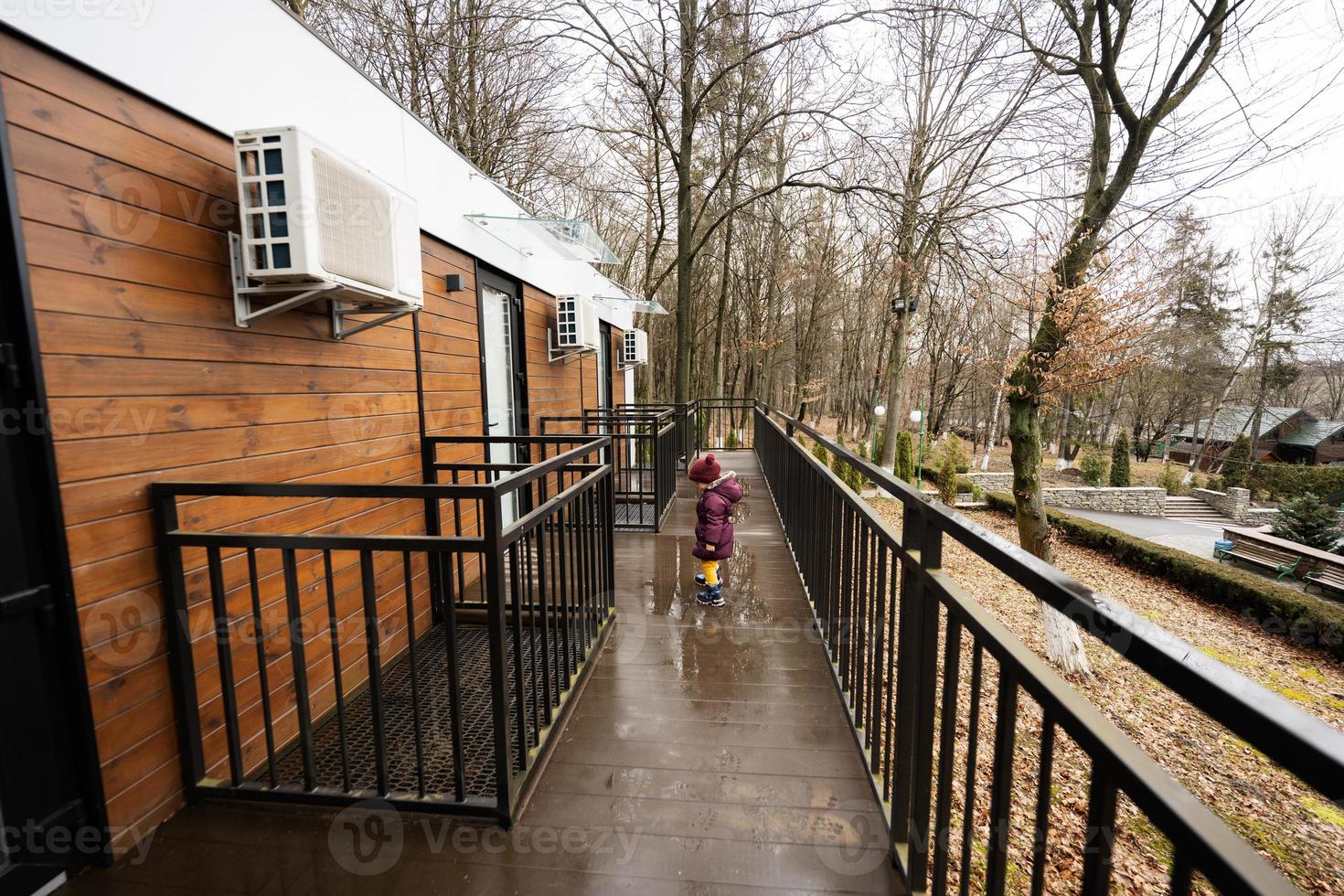 bebé niña caminando en terraza de un piso modular casas en primavera lluvioso bosque. foto