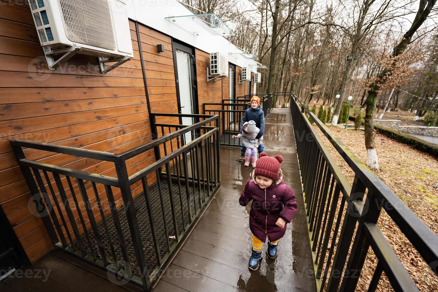Children walking on terrace of one-storey modular houses in spring rainy forest. photo