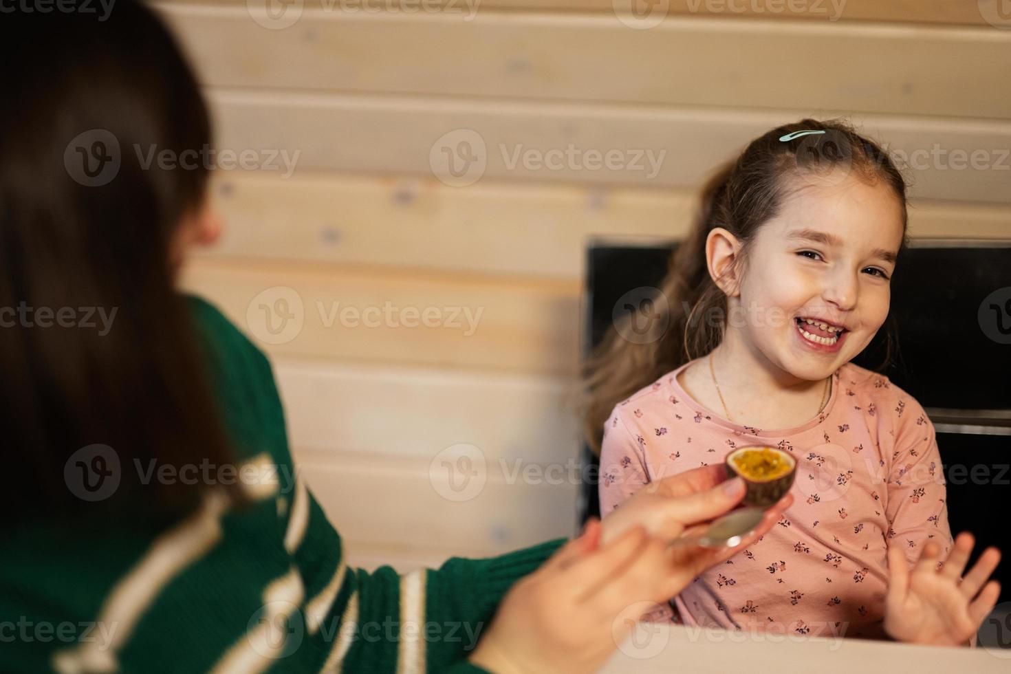 madre con hija comer frutas, ella dio un pasión fruta. foto