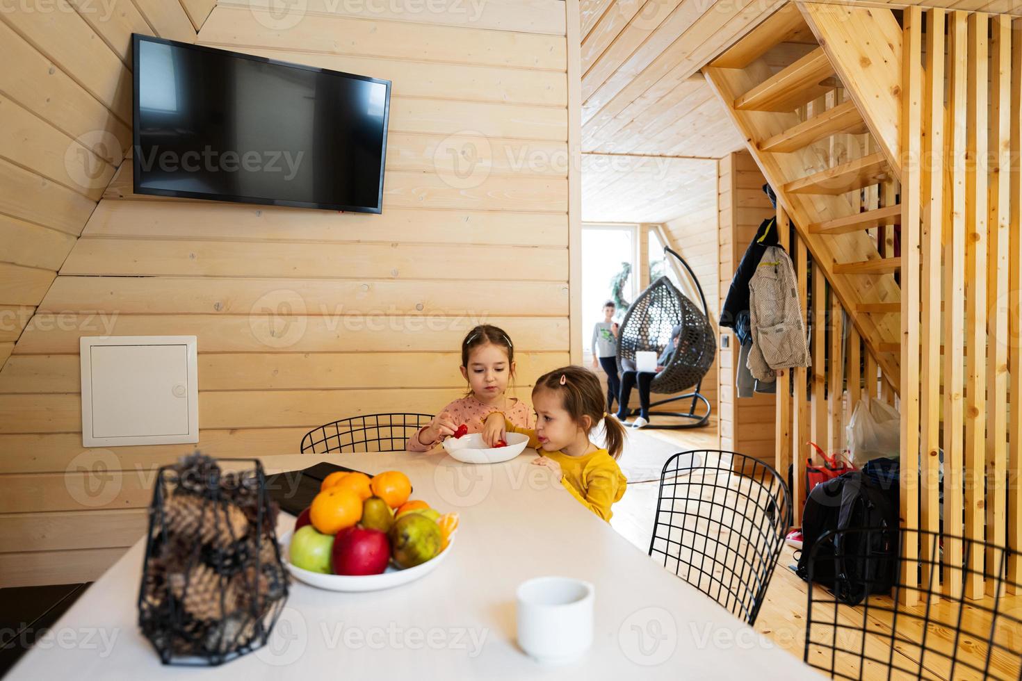 Two sisters eat strawberries in wooden country house on weekend. photo
