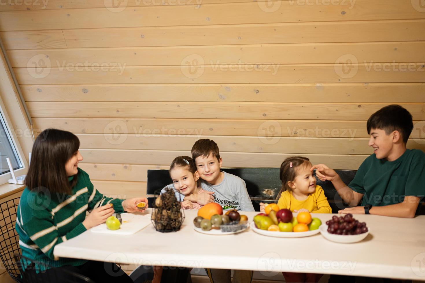 madre con cuatro niños comer frutas en de madera país casa en fin de semana. foto