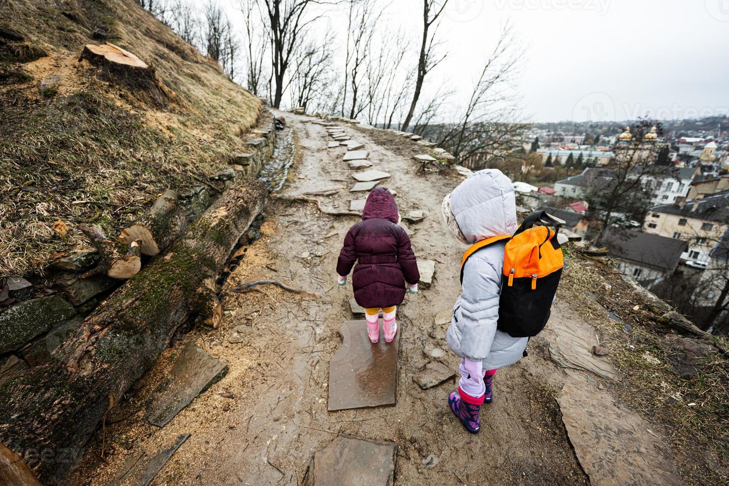 Two girls sisters walk up the wet path to an ancient fortress in rain. photo
