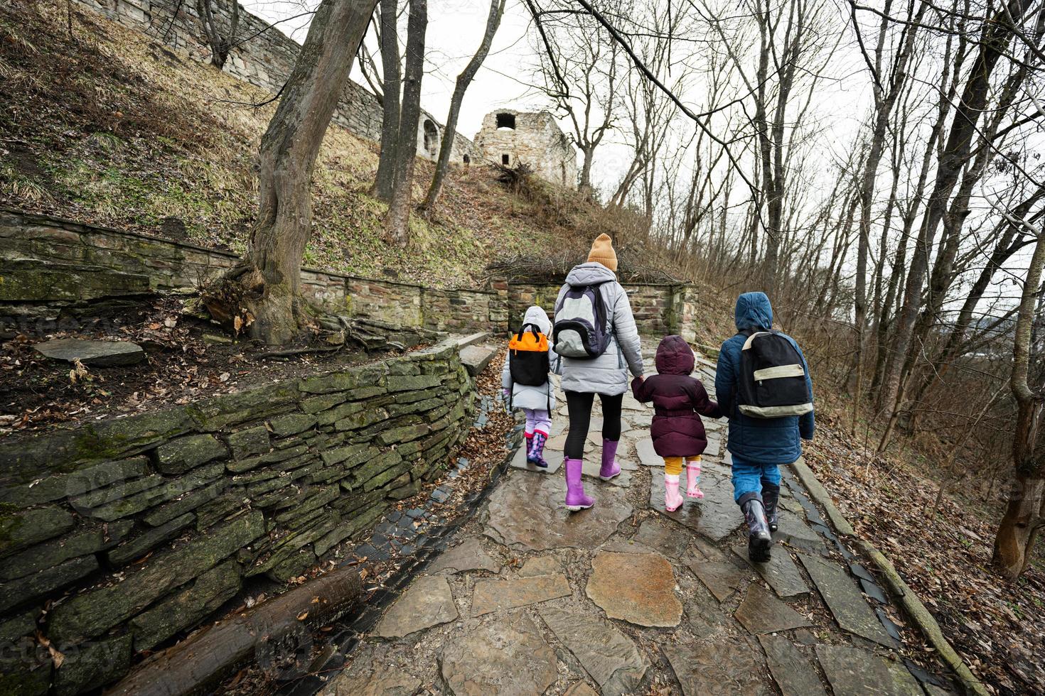 Back of mother and children walk up the wet path to an ancient medieval castle fortress in rain. photo