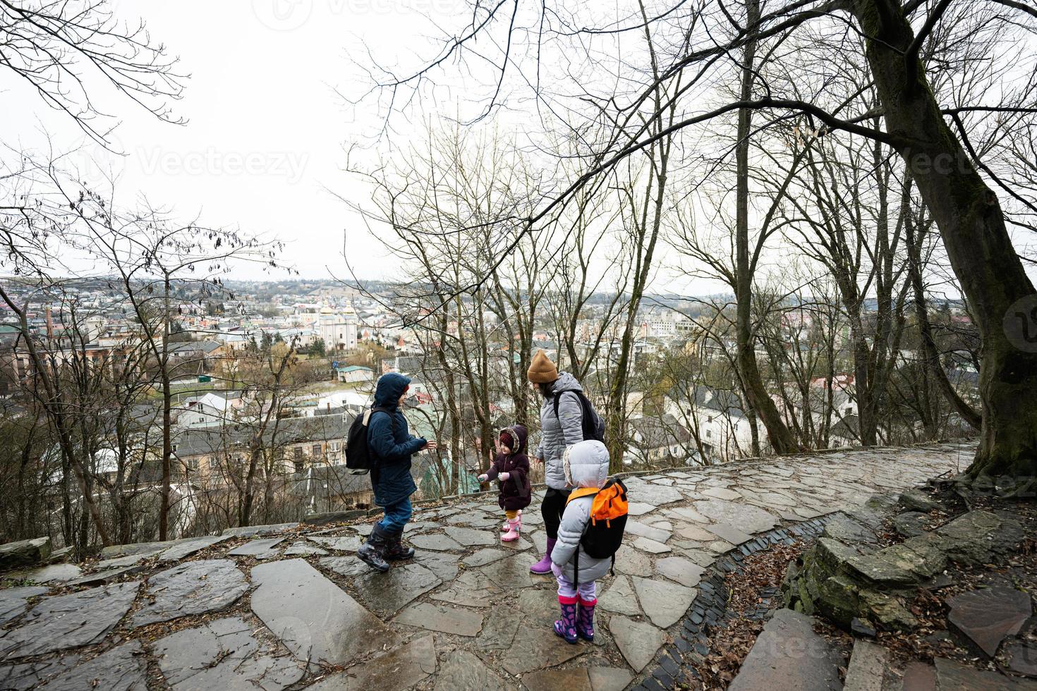 Mother and children walk up the wet path to an ancient medieval castle fortress in rain. photo