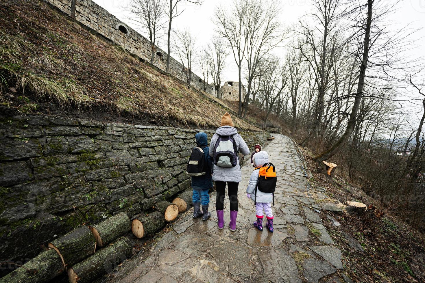 madre y niños caminar arriba el mojado camino a un antiguo medieval castillo fortaleza en lluvia. foto