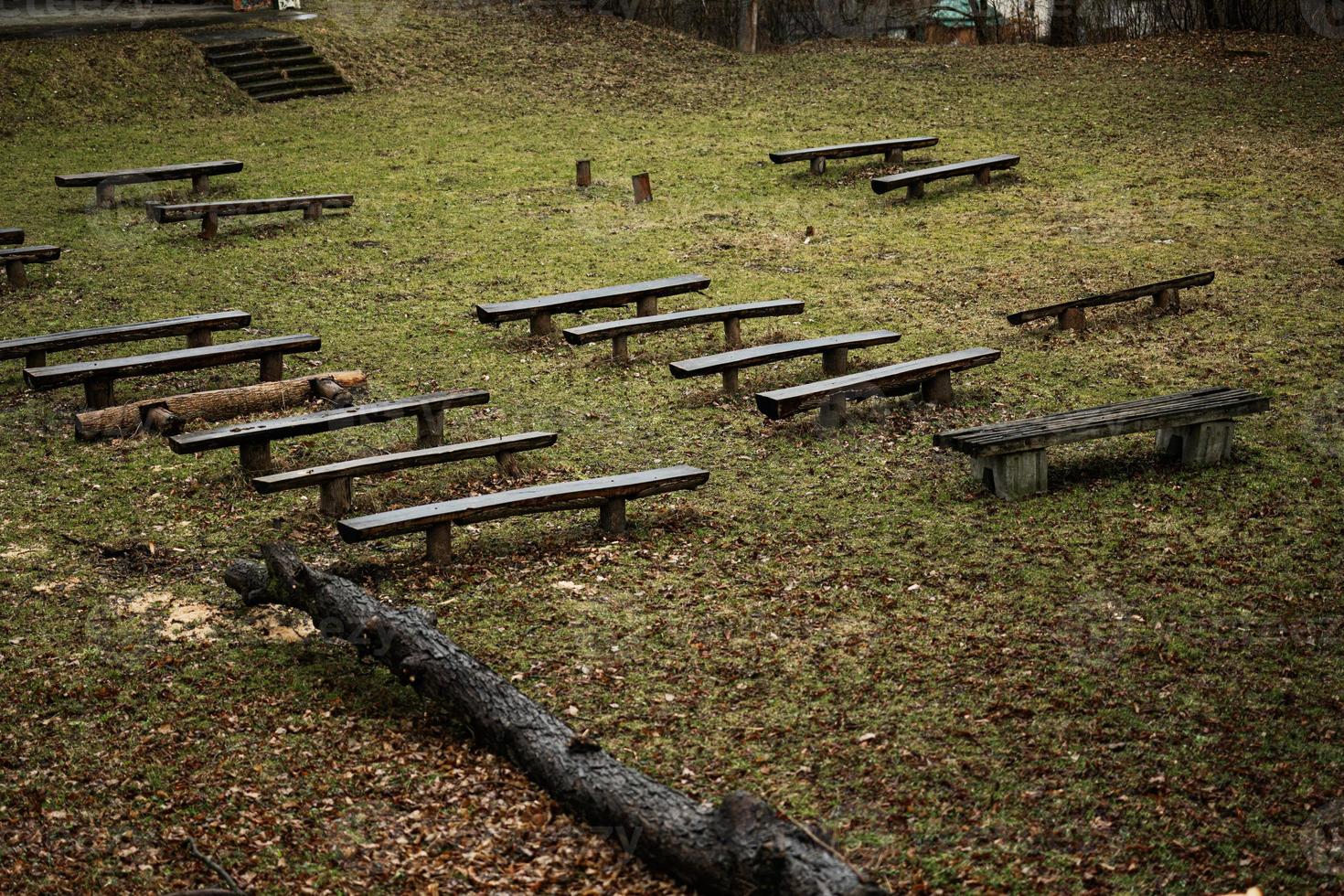 Row of wet wooden benches on alley. photo