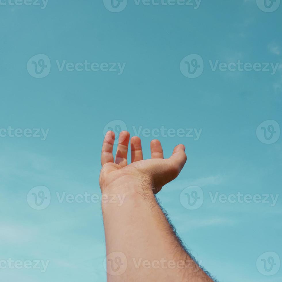 mano arriba gesticulando en el cielo azul, sentimientos y emociones foto