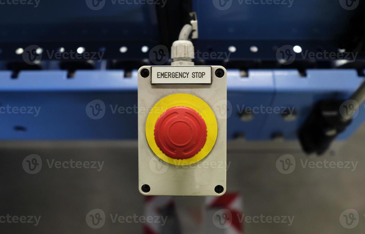 Button with the words EMERGENCY STOP next to a conveyor belt photo