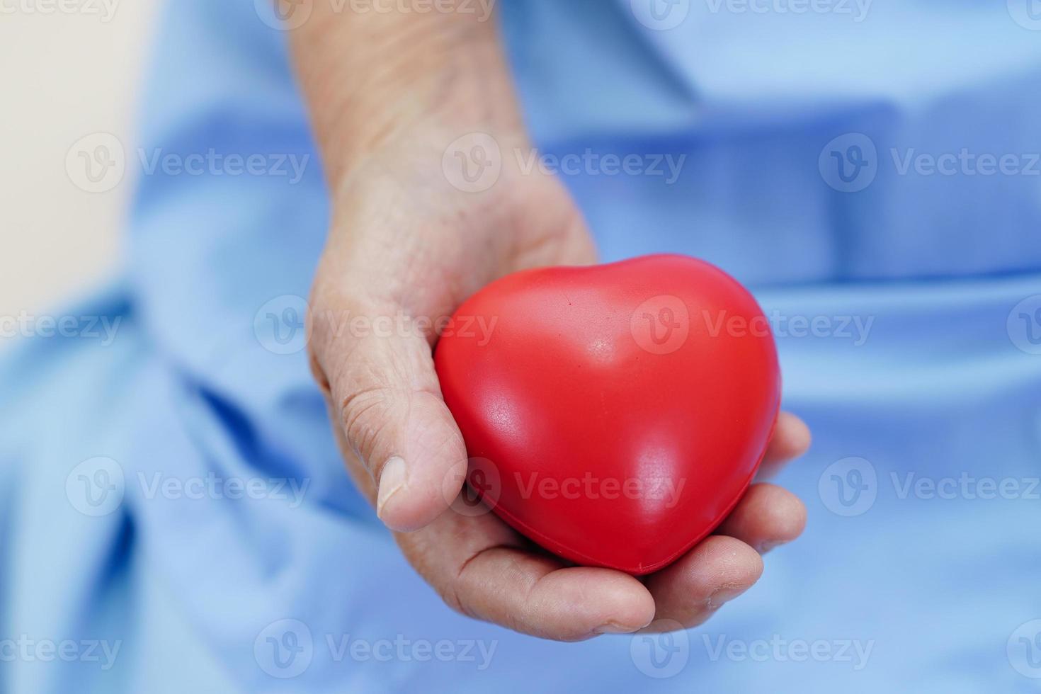 Asian elder senior woman patient holding red heart in hospital. photo