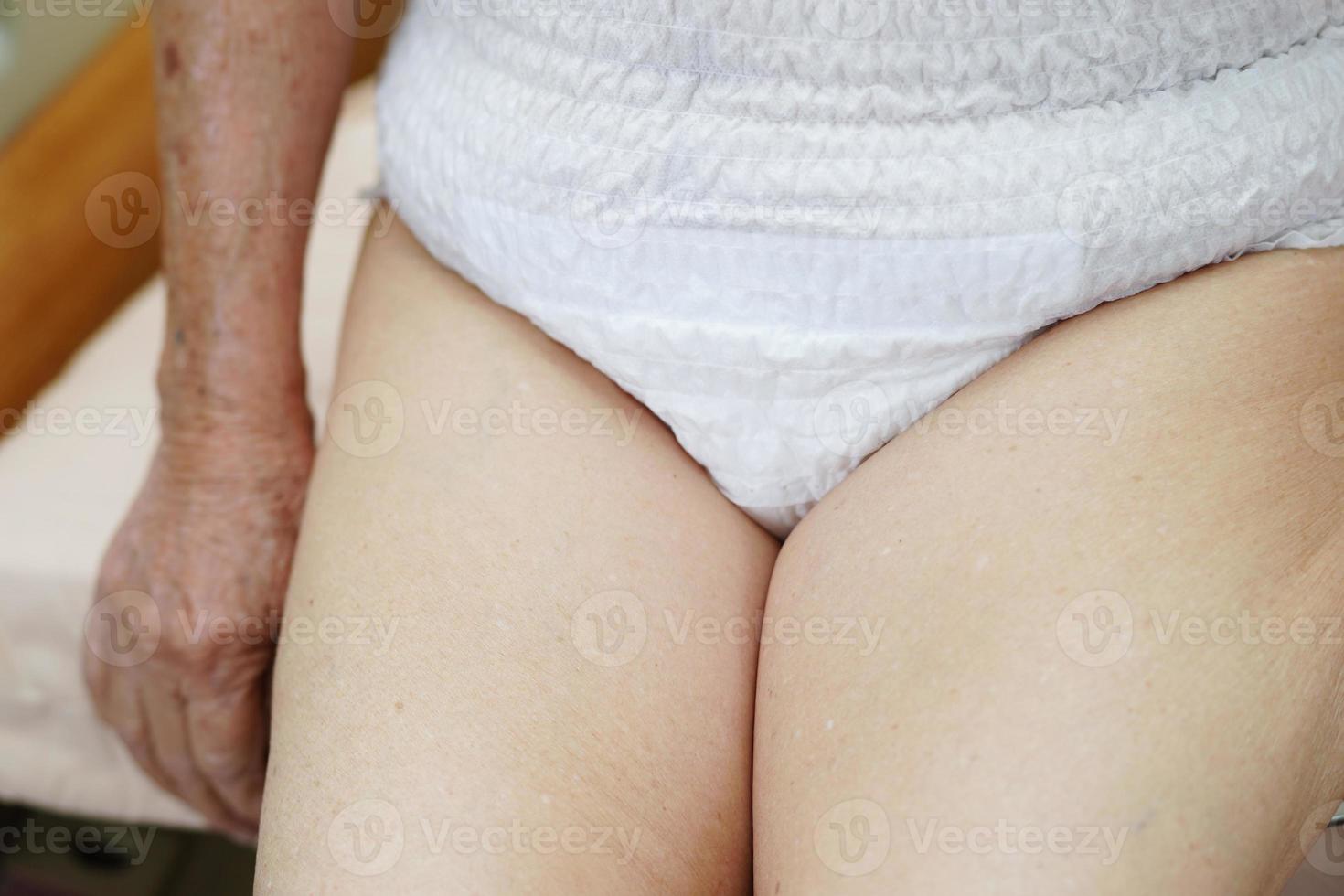 Asian elder senior woman patient wearing adult incontinence diaper pad in hospital. photo