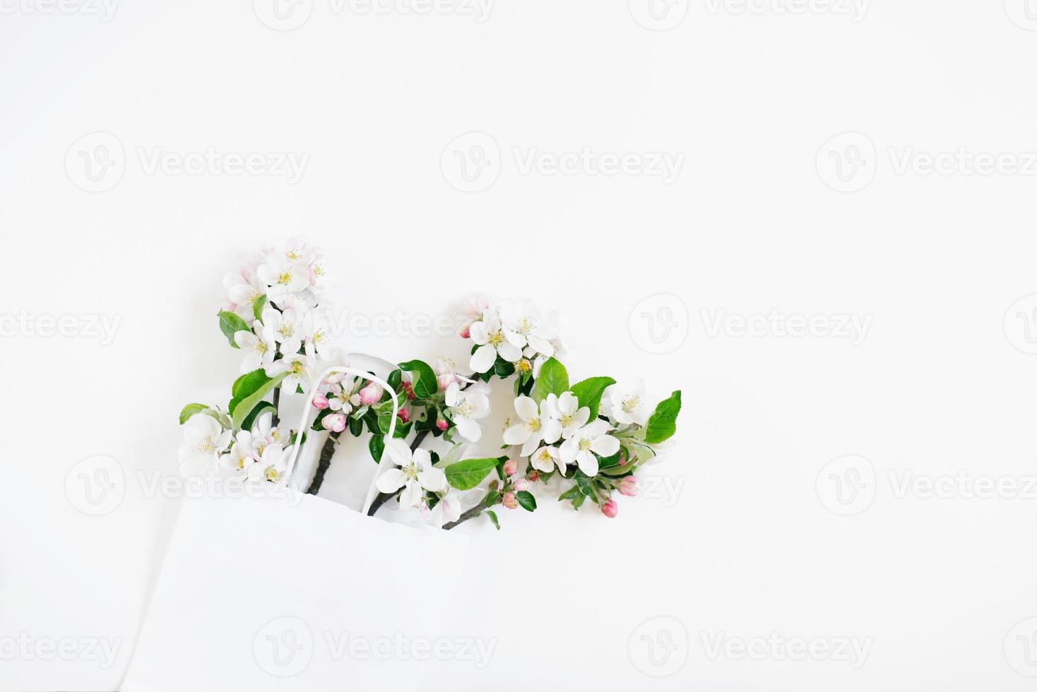 Many branches of an apple tree with flowers are in a paper shopping bag. Spring discounts and sales. Copy space, flat lay photo