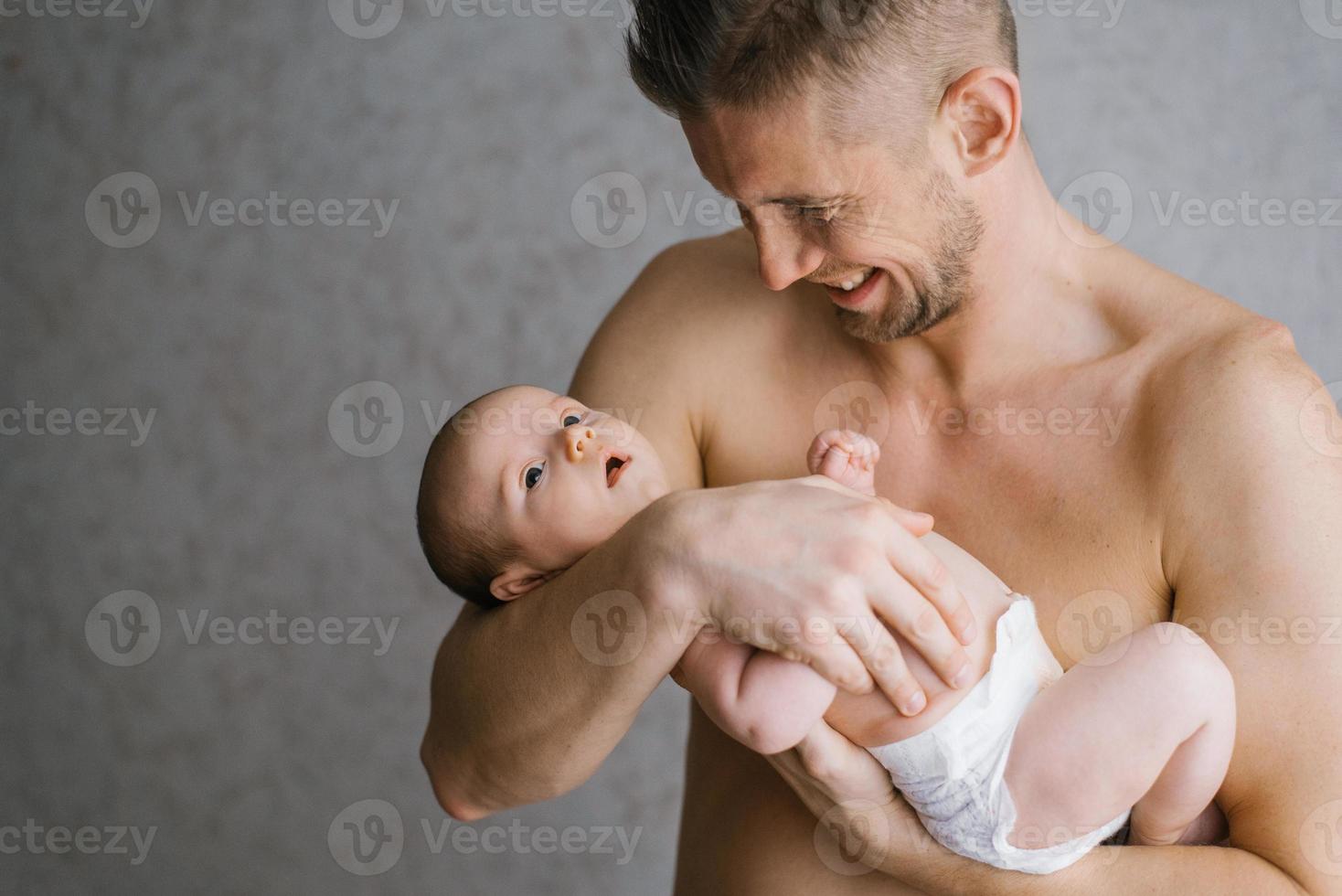 Father with a beard holds a newborn in his arms on a grey background. Holiday concept Fathers Day. photo