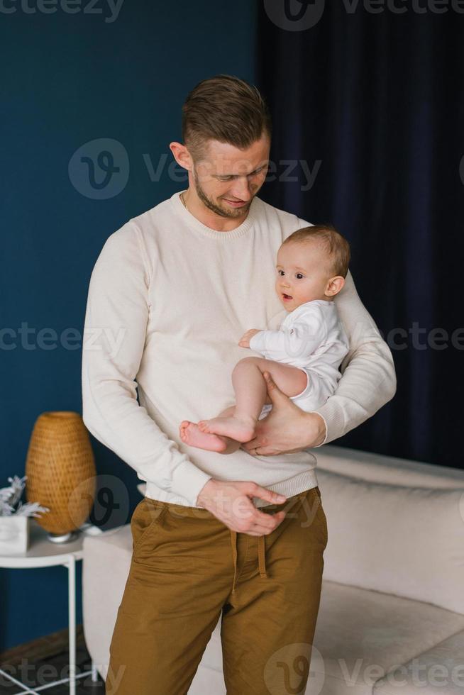 Happy father holds his baby son in his arms in the house photo