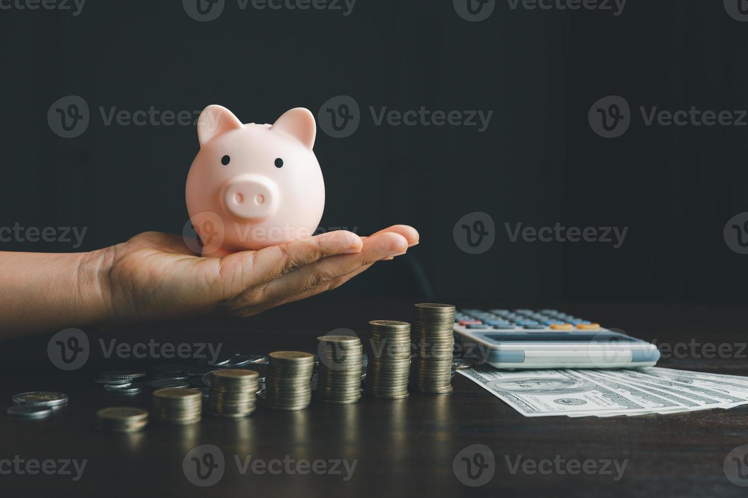 Business woman hand holding piggy bank on wood table background, saving money wealth and financial concept, finance, investment, Financial planning.Financial planning deposit for retirement. photo