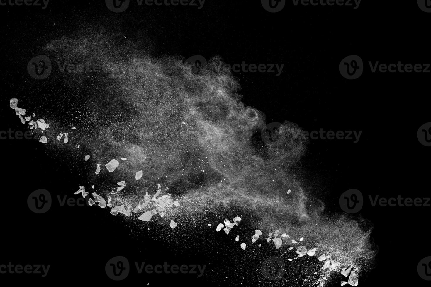 Split debris of  stone exploding with white powder against black background. photo