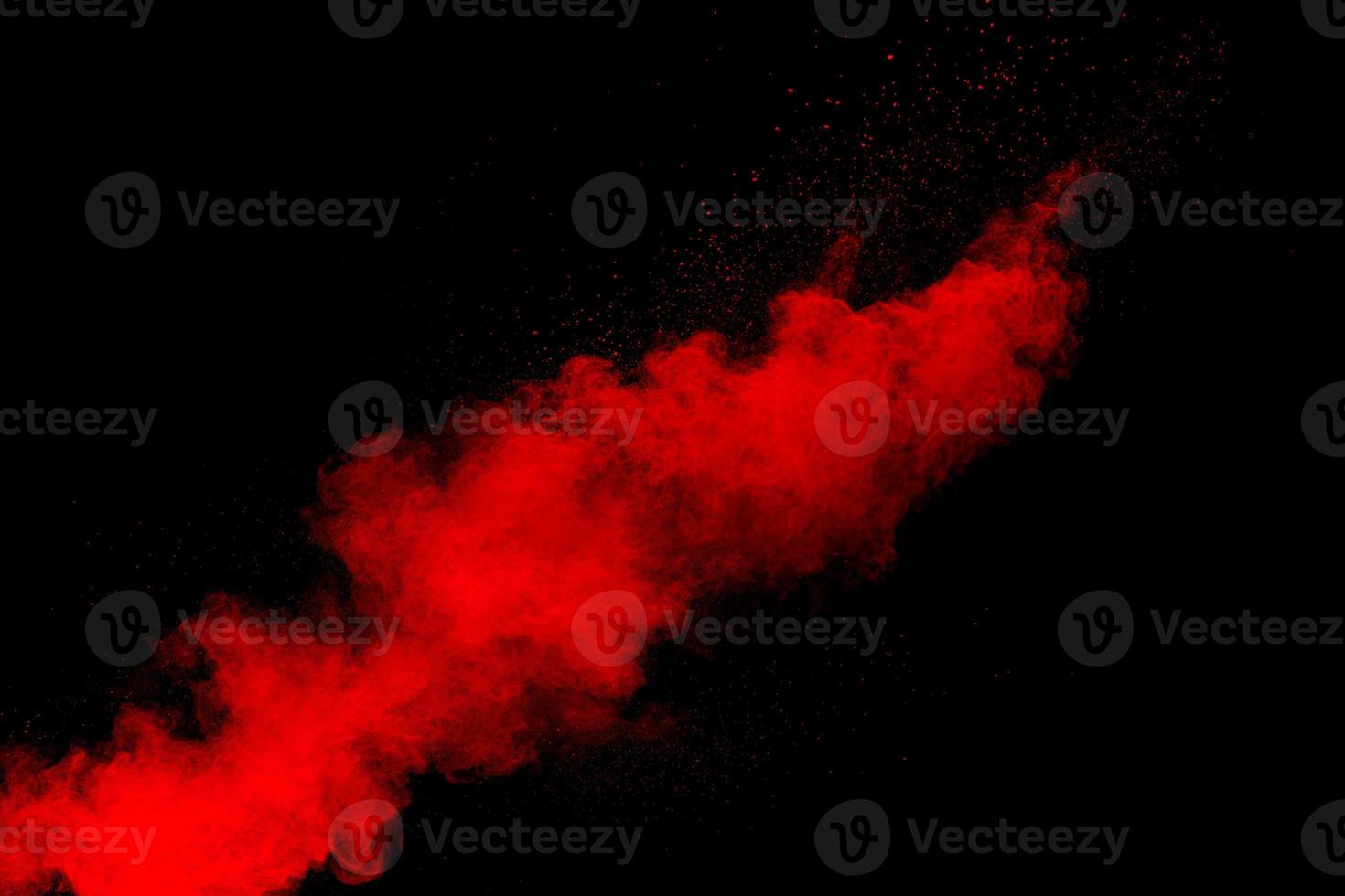 Red powder explosion cloud on black background. Freeze motion of red color dust  particles splashing. photo