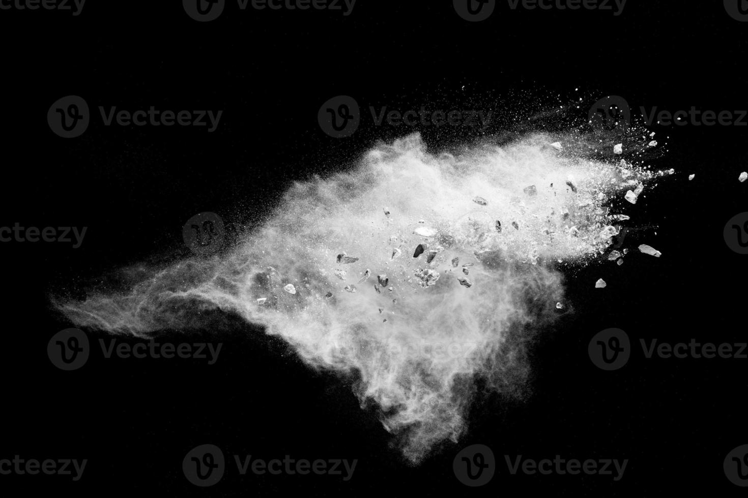 Split debris of  stone exploding with white powder against black background. photo